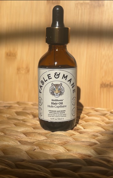 Fable & Mane HoliRoots hair oil bottle on a woven mat