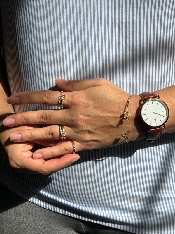 Hands with rings and a wristwatch against a striped shirt